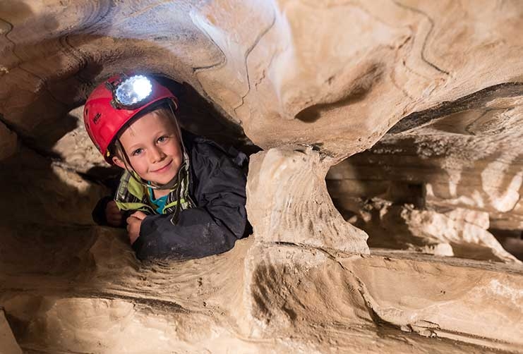 Kind mit Stirnlampe beim Erkunden der Spannaglhöhle am Hintertuxer Gletscher