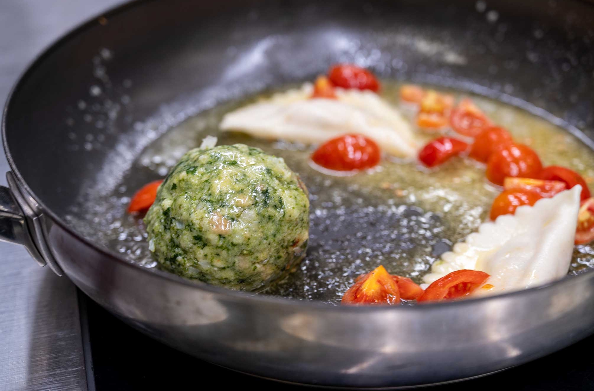 Spinatknödel und Tomaten werden in der Pfanne gebraten